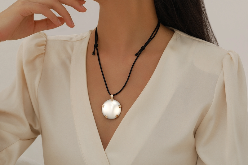 Woman holding BioElectric Shield pendant outdoors